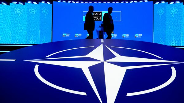 Hai người đàn ông đi ngang qua biểu tượng của NATO - Sputnik Việt Nam