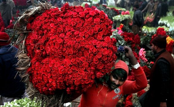 Người làm công mang bó hoa hồng tại chợ hoa ở Lahore, Pakistan. - Sputnik Việt Nam