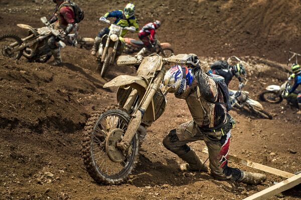 Thành viên giải đấu vô địch Enduro Red Bull Hare Scramble lôi chiếc mô tô của mình ra khỏi đống bùn - Sputnik Việt Nam