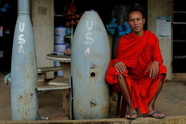 Nhà sư Phật giáo bên cạnh quả bom chưa nổ do quân đội Mỹ ném xuống trong chiến tranh Việt Nam, ở Xieng Khoảng (Lào) - Sputnik Việt Nam