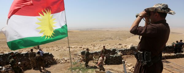 A flag of the autonomous Kurdistan region flies as Iraqi Kurdish Peshmerga fighters take position to monitor the area from their front line post in Bashiqa, a town 13 kilometres north-east of Mosul (File) - Sputnik Việt Nam