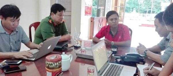 Trung úy Nguyễn Văn Thành (mặc áo đỏ) đang trả lời  báo chí về  việc xử lý vi phạm đối với chiếc xe chở trung tướng Võ Văn Liêm. - Sputnik Việt Nam