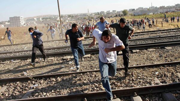 Turkish and Syrian Kurds run as Turkish security forces use tear gas to disperse them near the Mursitpinar border crossing on the Turkish-Syrian border, near the southeastern town of Suruc . file photo - Sputnik Việt Nam