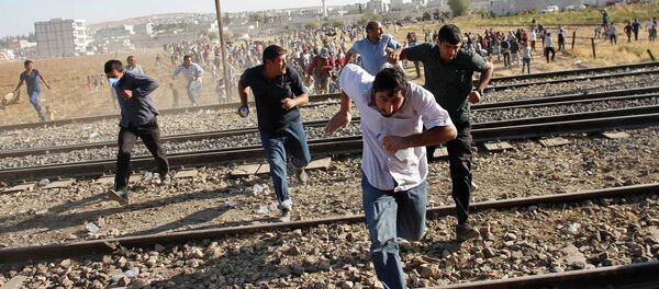 Turkish and Syrian Kurds run as Turkish security forces use tear gas to disperse them near the Mursitpinar border crossing on the Turkish-Syrian border, near the southeastern town of Suruc . file photo - Sputnik Việt Nam