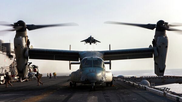 An AV-8B Harrier assigned to Marine Medium Tiltrotor Squadon 266, descends onto the flight deck of the USS Kearsarge as an MV-22B Osprey prepares to takeoff, at sea, May 27, 2013 - Sputnik Việt Nam