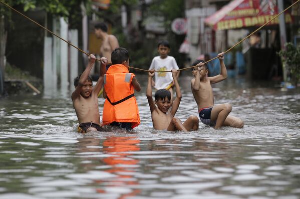 Philippines. Manila sau cơn bão nhiệt đới. Các cậu bé dù sao cũng cứ vui nhộn chơi nghịch trong nước lụt ... - Sputnik Việt Nam