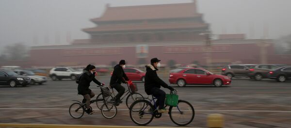 People wearing masks cycle past Tiananmen Gate during the smog after a red alert was issued for heavy air pollution in Beijing, China, December 20, 2016. - Sputnik Việt Nam