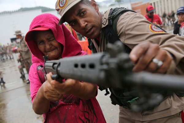 Venezuela. Cảnh sát quân đội hướng dẫn một  người phụ nữ cao tuổi ở Caracas sử dụng vũ khí. - Sputnik Việt Nam