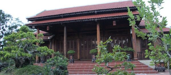 Căn nhà rường gỗ được xây dựng trong khuôn viên vườn, xung quanh bao bởi tường bê tông, có cây cối - Sputnik Việt Nam