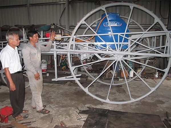 Phạm Văn Hát (bên phải) giới thiệu với khách hàng chiếc máy phun thuốc trừ sâu. - Sputnik Việt Nam