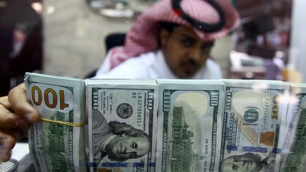 A Saudi money changer, pictured through a glass, arranges U.S banknotes at a currency exchange shop in Riyadh, Saudi Arabia September 29, 2016 - Sputnik Việt Nam