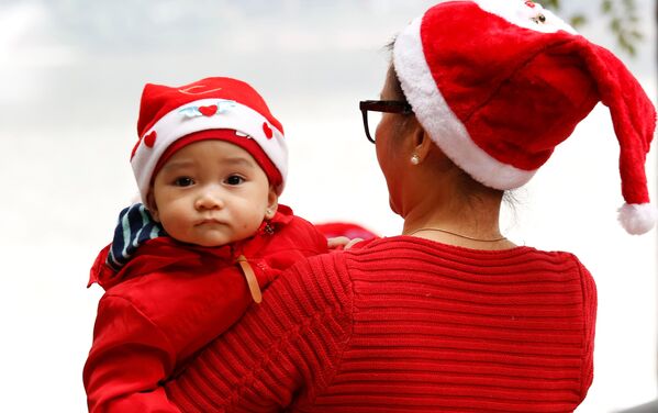 Bà và cháu trong bộ trang phục Ông già Noel bên Hồ Hoàn Kiếm ở Hà Nội, Việt Nam - Sputnik Việt Nam