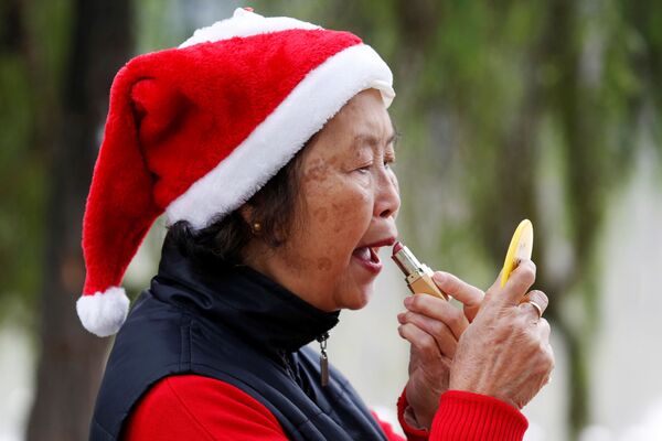 Một người phụ nữ đội chiếc mũ của Ông già Noel đang trang điểm bên Hồ Hoàn Kiếm ở Hà Nội, Việt Nam - Sputnik Việt Nam