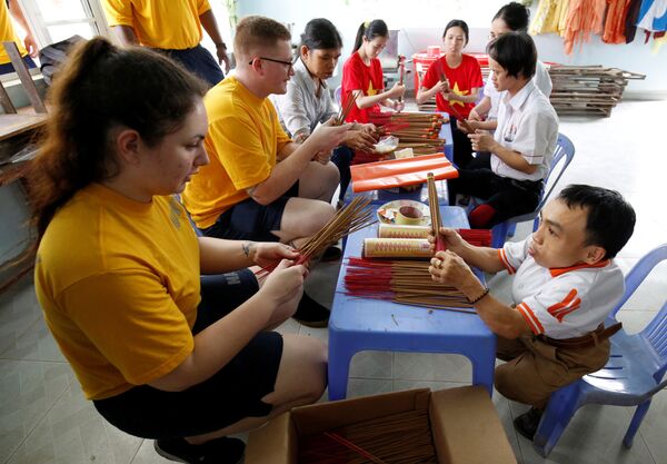 Những người lính Hải quân Mỹ trên tàu sân bay USS Carl Vinson học làm nhang trẻ em bị nhiễm chất độc da cam ở Trung tâm bảo trợ nạn nhân chất độc da cam và trẻ em bất hạnh Thành phố Đà Nẵng. - Sputnik Việt Nam