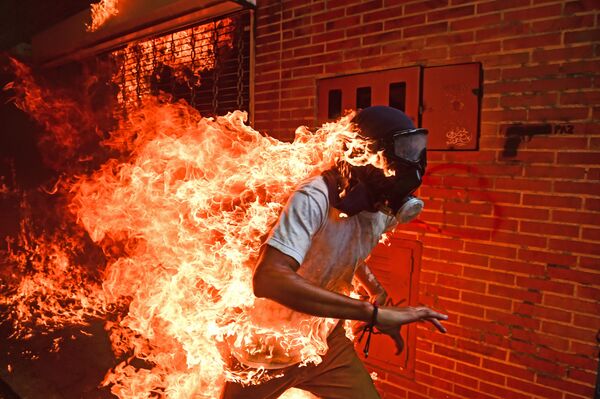 Giải thưởng chính của cuộc thi World Press Photo thuộc về nhiếp ảnh gia Venezuela Ronaldo Shemidt với bức ảnh chụp ngọn lửa bao trùm một người đàn ông đang chạy với mặt nạ phòng độc. - Sputnik Việt Nam