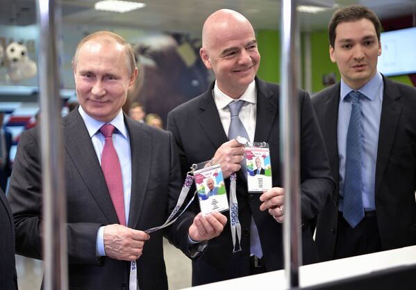 Tổng thống Nga Vladimir Putin và Chủ tịch FIFA Gianni Infantino với những tấm hộ chiếu người hâm mộ xem giải bóng đá World Cup 2018 ở Nga - Sputnik Việt Nam