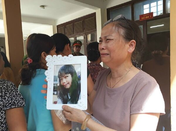 Bà Nguyễn Thị Thu ôm di ảnh con gái, khóc lớn trước cửa phòng xử. - Sputnik Việt Nam