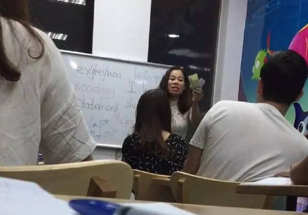 Cô Tuyến cầm tiền nộp phạt giơ lên trước lớp trong khi tranh cãi với học viên. Cô Tuyến cầm tiền nộp phạt giơ lên trước lớp trong khi tranh cãi với học viên. - Sputnik Việt Nam