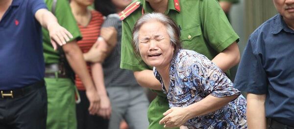 Người thân khóc nghẹn khi lực lượng chức năng đưa thi thể bà cụ ra ngoài. - Sputnik Việt Nam