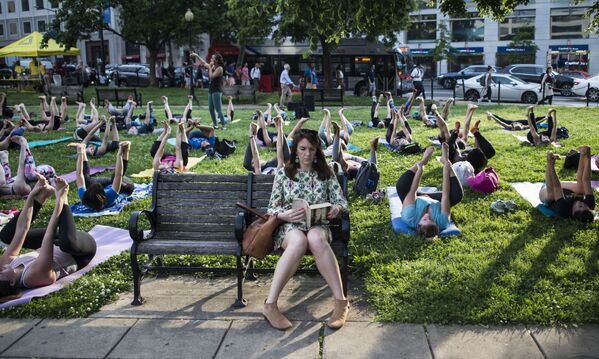 Người phụ nữ đọc sách trong buổi tập của nhóm yoga ở Washington, DC, Hoa Kỳ - Sputnik Việt Nam