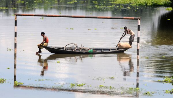 Những người dân địa phương đang đi trên thuyền qua khung thành bóng đá bị ngập dưới nước ở làng Mekata, Ấn Độ - Sputnik Việt Nam