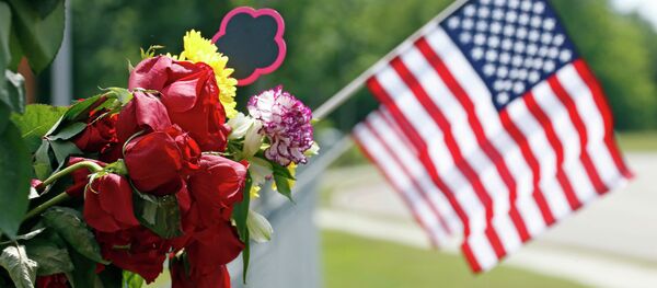 An American flag hangs next to bouquets of flowers on a barbed wire fence Sunday, May 10, 2015, at a makeshift memorial near the site where two Hattiesburg, Miss., police officers were shot to death during a Saturday evening traffic stop - Sputnik Việt Nam