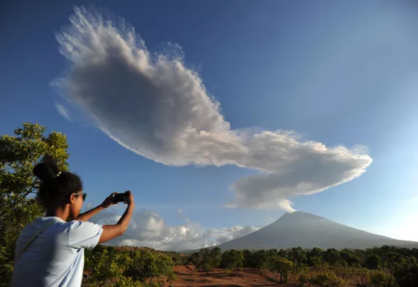 Một phụ nữ đang chụp ảnh núi lửa Agung đang bốc khói trên đảo Bali - Sputnik Việt Nam