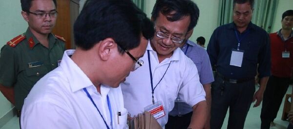 Ông Mai Văn Trinh kiểm tra quy cách niêm phong túi đựng bài thisáng 3/7 tại hội đồng thi Hòa Bình - Sputnik Việt Nam