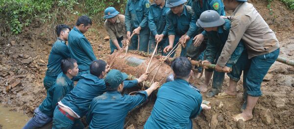 Chiến sỹ lực lượng vũ trang đưa bom xuống hố để hủy nổ. - Sputnik Việt Nam