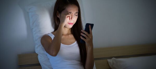 Cô gái nhìn vào điện thoại trên giường - Sputnik Việt Nam