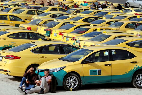 Lái xe ngồi trên mặt đất bên cạnh xe taxi ở thủ đô Amman của Jordan - Sputnik Việt Nam