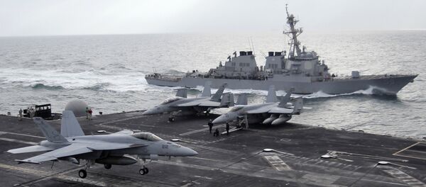 This file photo taken on Monday, Feb. 13, 2012 shows a U.S. F-18 fighter jet, left, land on the Nimitz-class aircraft carrier USS Abraham Lincoln (CVN 72) as a U.S. destroyer sells on alongside during fly exercises in the Persian Gulf - Sputnik Việt Nam