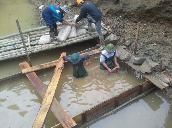 Công nhân địa phương mặc đồ bảo hộ ngâm mình dưới nước lạnh 5 độ để xử lý móng trụ cầu Nà Giỏ - Sputnik Việt Nam