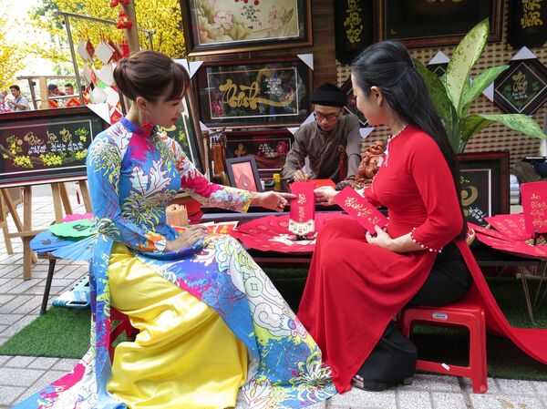 Du khách lựa chọn thư pháp tại phố ông đồ “Trẻ”.  - Sputnik Việt Nam