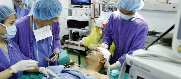 PGS.TS Đồng Văn Hệ, Phó Giám đốc bệnh viện Hữu nghị Việt Đức nói chuyện với bệnh nhân ngay trên bàn phẫu thuật ca u não bằng phương pháp “Mổ thức tỉnh” lần đầu tiên tại Việt Nam. - Sputnik Việt Nam