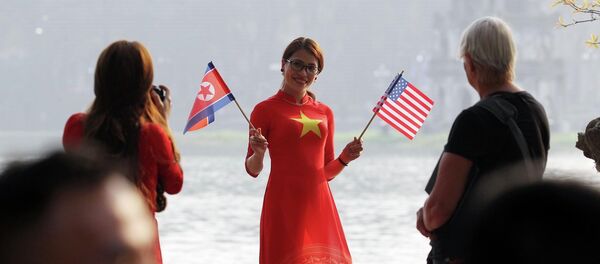 Thiếu nữ Việt Nam cầm cờ Mỹ và Triều Tiên chào mừng hội nghị.  - Sputnik Việt Nam
