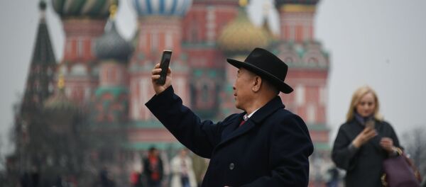 Турист фотографируется на Красной площади в Москве, на фоне храма Василия Блаженного Турист фотографируется на Красной площади в Москве, на фоне храма Василия Блаженного - Sputnik Việt Nam