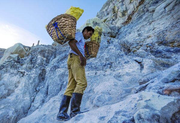  Thợ mỏ khuân vác túi lưu huỳnh từ mỏ đá trên núi lửa Kawah Ijen đang hoạt động ở Indonesia - Sputnik Việt Nam