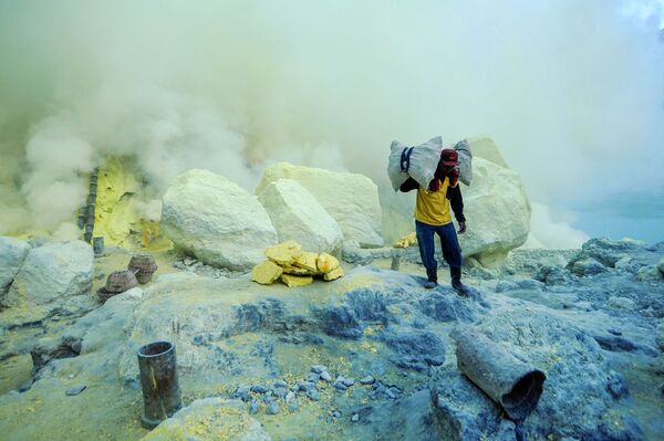  Thợ mỏ khuân vác túi lưu huỳnh từ mỏ đá trên núi lửa Kawah Ijen đang hoạt động ở Indonesia - Sputnik Việt Nam