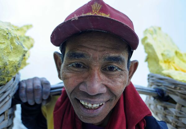  Thợ mỏ khuân vác túi lưu huỳnh từ mỏ đá trên núi lửa Kawah Ijen đang hoạt động ở Indonesia - Sputnik Việt Nam