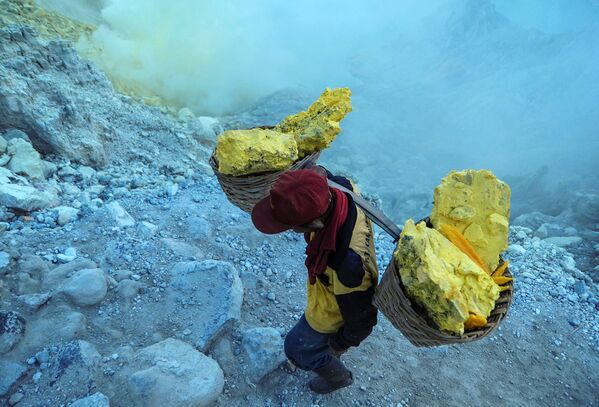  Thợ mỏ khuân vác túi lưu huỳnh từ mỏ đá trên núi lửa Kawah Ijen đang hoạt động ở Indonesia - Sputnik Việt Nam