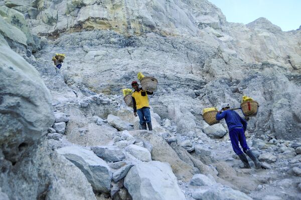  Thợ mỏ khuân vác túi lưu huỳnh từ mỏ đá trên núi lửa Kawah Ijen đang hoạt động ở Indonesia - Sputnik Việt Nam