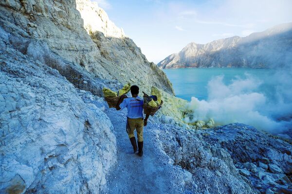  Thợ mỏ khuân vác túi lưu huỳnh từ mỏ đá trên núi lửa Kawah Ijen đang hoạt động ở Indonesia - Sputnik Việt Nam