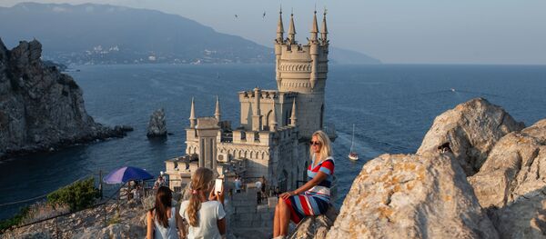 Отдыхающие фотографируются возле замка Ласточкино гнездо на береговой скале в поселке Гаспра в Крыму Отдыхающие фотографируются возле замка Ласточкино гнездо на береговой скале в поселке Гаспра в Крыму - Sputnik Việt Nam