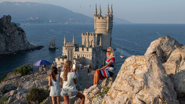 Отдыхающие фотографируются возле замка Ласточкино гнездо на береговой скале в поселке Гаспра в Крыму - Sputnik Việt Nam