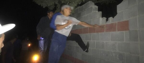 Люди перелезают через забор на месте задержания экс-президента Киргизии Алмазбека Атамбаева - Sputnik Việt Nam