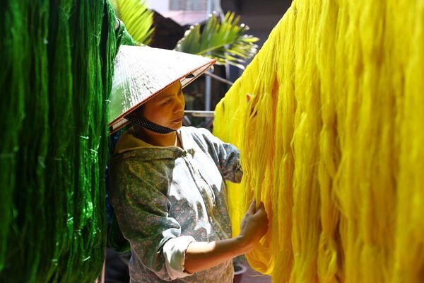 Phơi tơ sau khi đã được nhuộm màu tại xưởng dệt của gia đình nghệ nhân Nguyễn Anh Sơn. Không phải loại tơ nào cũng đem nhuộm mà có loại để trắng tinh khiết, ngả vàng ngà như lụa nõn; có loại được nhuộm màu ngay từ khâu sợi như gấm, vóc.  - Sputnik Việt Nam