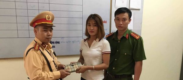 Thiếu tá Nguyễn Minh Tuấn cùng cán bộ Công an thị trấn Văn Điển trao tận tay chiếc ví bên trong có đầy đủ tài sản cho chị Đỗ Phương Anh  - Sputnik Việt Nam