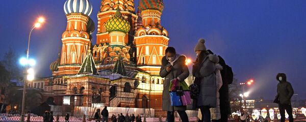 Khách du lịch nước ngoài đeo khẩu trang bảo vệ chụp ảnh gần Nhà thờ Thánh St. Basil trên Quảng trường Đỏ ở Moskva - Sputnik Việt Nam