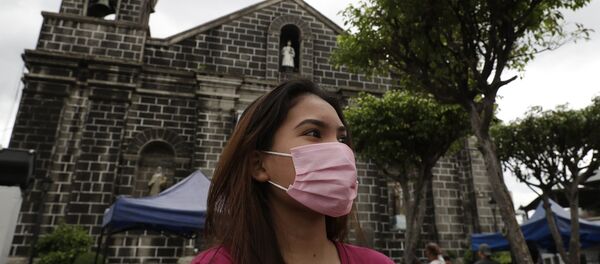 Người phụ nữ đeo khẩu trang ra khỏi nhà thờ ở Mandaluyong, phía đông Manila, Philippines - Sputnik Việt Nam
